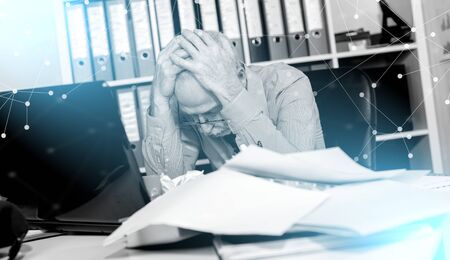 Overworked businessman sitting at a messy desk in office
