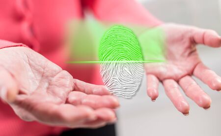 Fingerprint security system concept above the hands of a woman in backgroundの写真素材