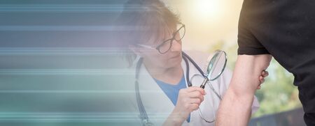 Dermatologist examining the skin on the arm of a patient; light effectの写真素材