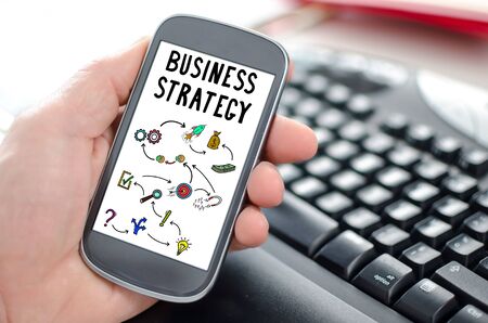 Hand holding a smartphone showing a business strategy conceptの写真素材