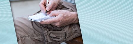 Man sitting outdoor taking notes on a pocket book; panoramic bannerの写真素材