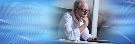 Portrait of thoughtful senior businessman sitting in office, hard light; panoramic banner
