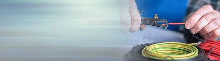 Electrician hands stripping a wire. panoramic bannerの写真素材