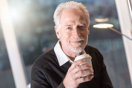 Portrait of senior businessman having coffee break in office