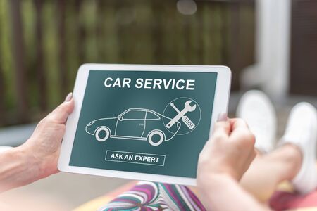 Female hands holding a tablet with car service conceptの写真素材