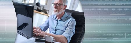 Portrait of senior businessman working on laptop in office, hard light; panoramic bannerの写真素材