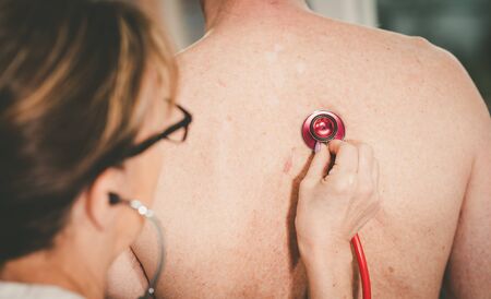 Female doctor using stethoscope to exam patientの写真素材