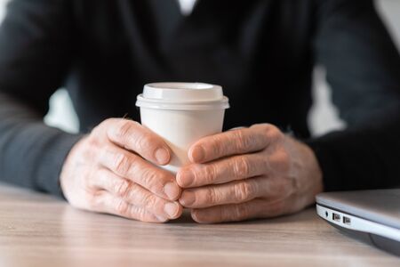 Businessman holding a paper coffee cup during break