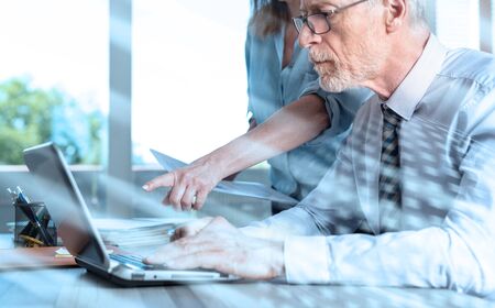 Business people working on laptop in office; multiple exposureの写真素材
