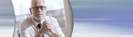 Portrait of mature businessman sitting in office. panoramic bannerの写真素材
