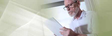 Senior businessman using a digital tablet in office, hard light. panoramic banner