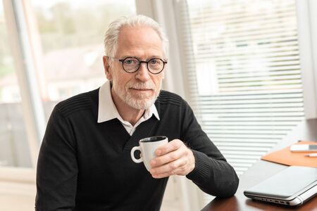 Portrait of businessman having coffee break at office