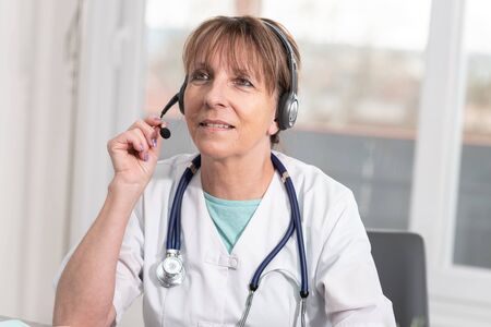 Portrait of mature female doctor during online medical consultation