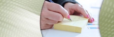 Businesswoman taking notes on a post-it; panoramic banner