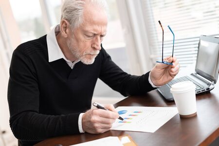 Senior businessman analysing marketing graphs at office