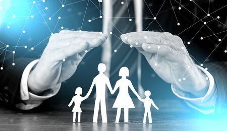 Concept of family insurance with hands protecting a family, light effectの写真素材