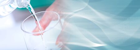 Pouring water into a glass, closeup; panoramic bannerの写真素材