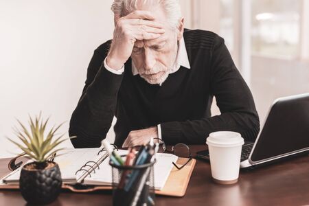 Portrait of overworked senior businessman sitting in office
