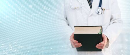 Doctor standing and holding a medical textbook; multiple exposureの写真素材