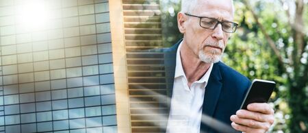 Mature man using his mobile phone outdoors; multiple exposureの写真素材