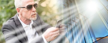 Mature man using his mobile phone outdoors, light effect; multiple exposure
