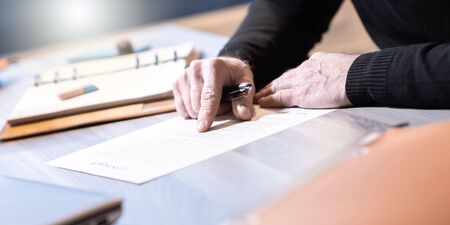 Senior businessman reviewing terms of contract at officeの写真素材