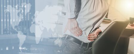 Businessman suffering from back pain in office, light effect; multiple exposure