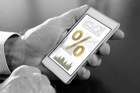 Hand holding a smartphone with interest rates conceptの写真素材