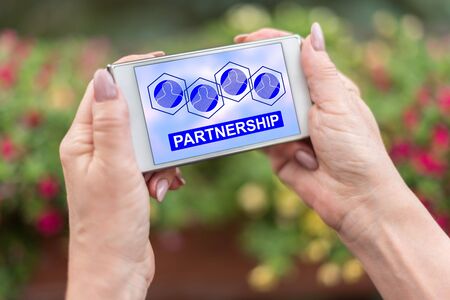 Female hands holding a smartphone with partnership conceptの写真素材