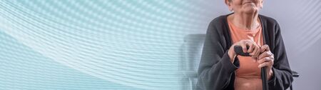 Senior woman sitting with her cane; panoramic banner