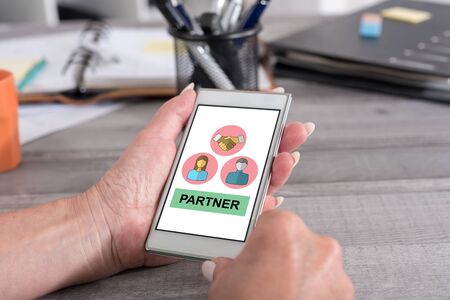 Female hand holding a smartphone with partner conceptの写真素材