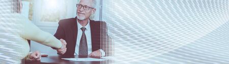 Smiling adviser shaking hand with client after signing a contract, light effect. panoramic banner