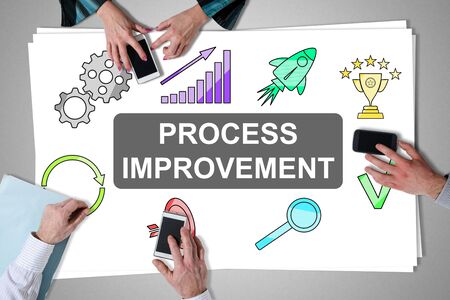 Process improvement concept placed on a desk with hands using smartphonesの写真素材