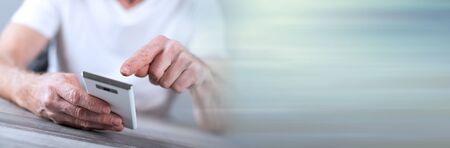 Man sitting using a smartphone; panoramic bannerの写真素材