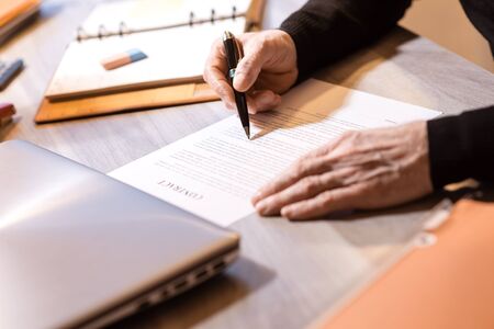 Senior businessman reviewing terms of contract at officeの写真素材