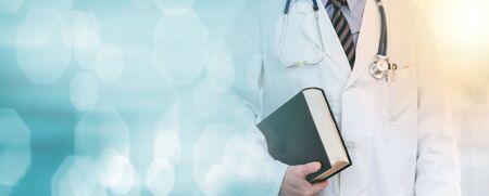 Doctor standing and holding a medical textbook; light effectの写真素材