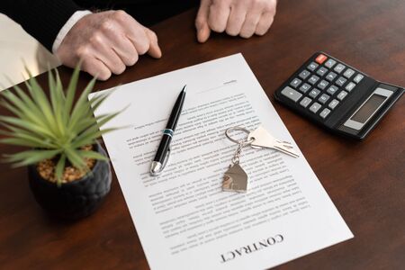 Hands of customer in front of real estate contract with house keys before signingの写真素材