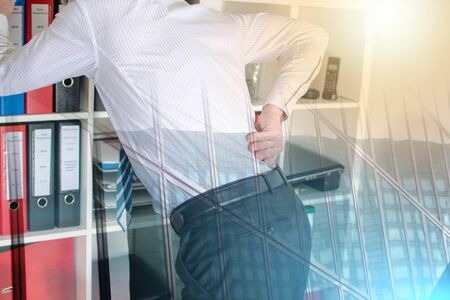 Businessman with back pain at office; multiple exposureの写真素材