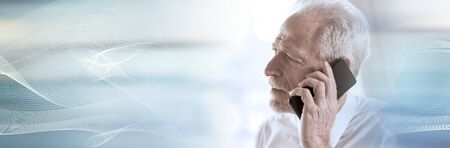 Portrait of senior businessman talking on mobile phone; panoramic bannerの写真素材