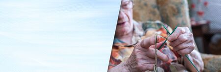 Senior woman knitting at home; panoramic bannerの写真素材