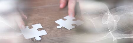 Hands joining two puzzle pieces, teamwork concept; panoramic banner