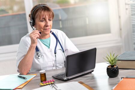 Portrait of mature female doctor during online medical consultationの写真素材