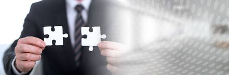 Hands joining two puzzle pieces, teamwork concept; panoramic banner