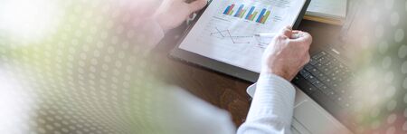 Businessman analysing economic graphs at office; panoramic banner