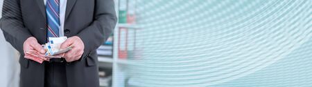 Businessman counting his money at office; panoramic bannerの写真素材