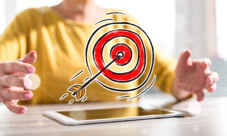 Digital tablet with business target concept between hands of a woman in backgroundの写真素材
