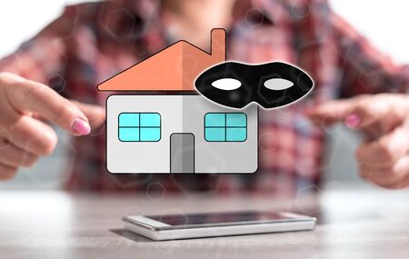 Smartphone with home burglary concept between hands of a woman in backgroundの写真素材