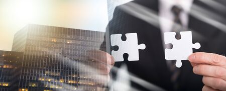 Hands joining two puzzle pieces, teamwork concept; multiple exposureの写真素材