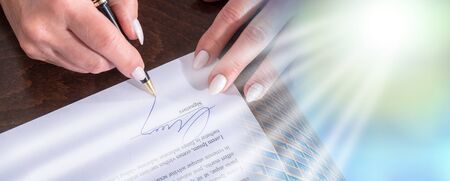 Female hand signing a contract; light effectの写真素材