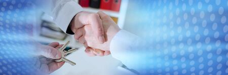 Realtor shaking hands with his client by delivering the keys, closeup; panoramic bannerの写真素材